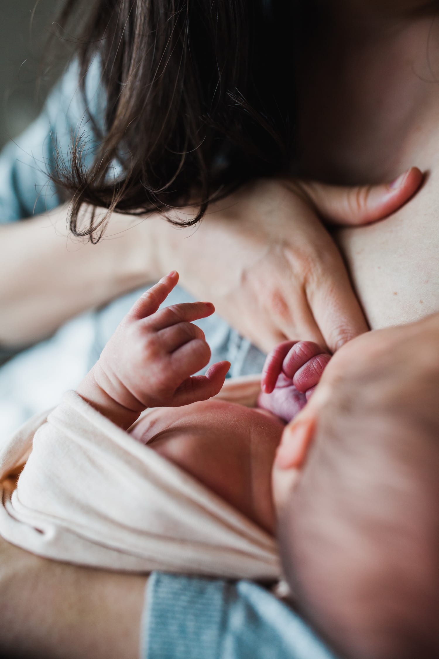 Close-up of the newborn's tiny hands wrapped around mom's finger