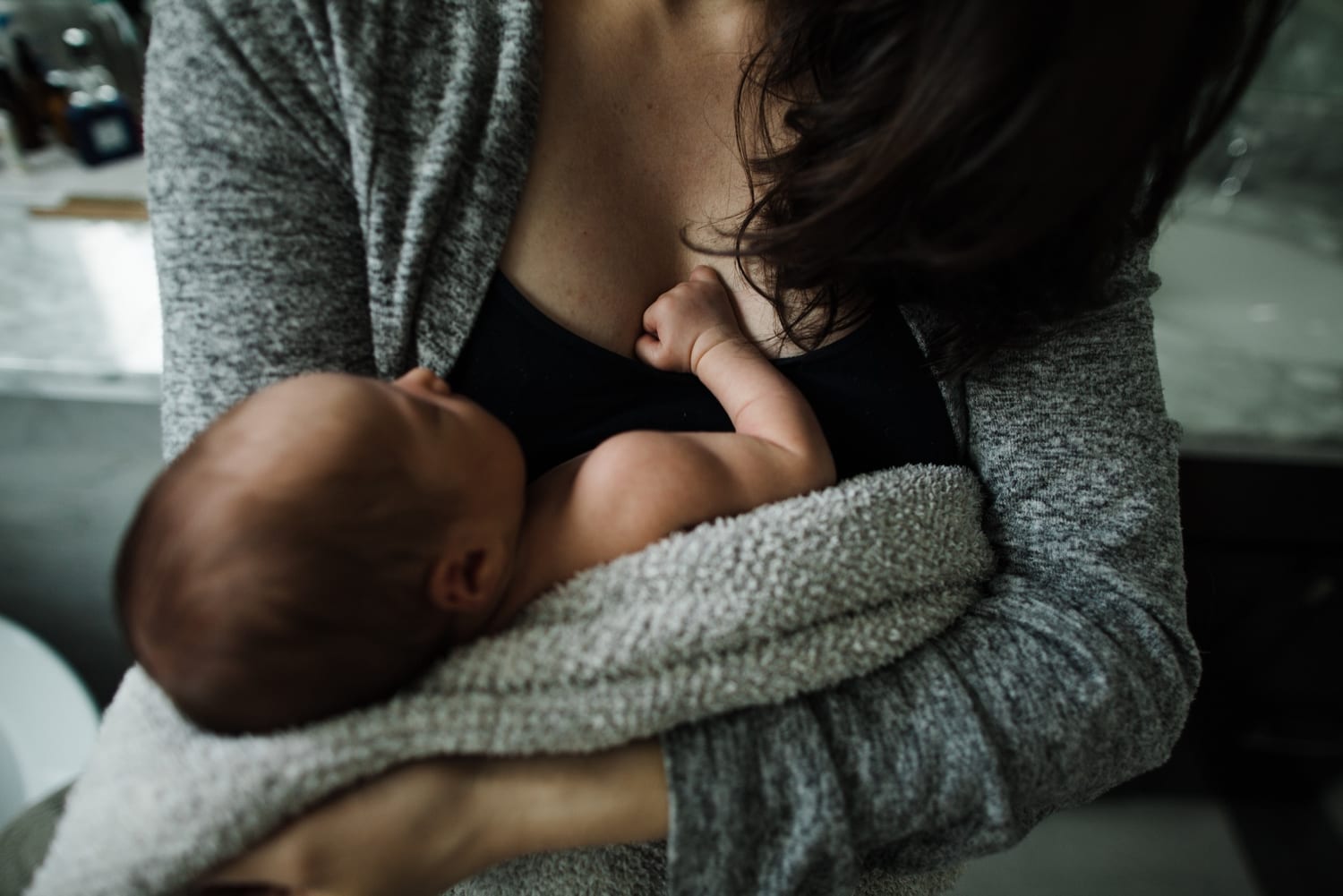 Newborn snuggled at mom's chest, one tiny fist pressed against her