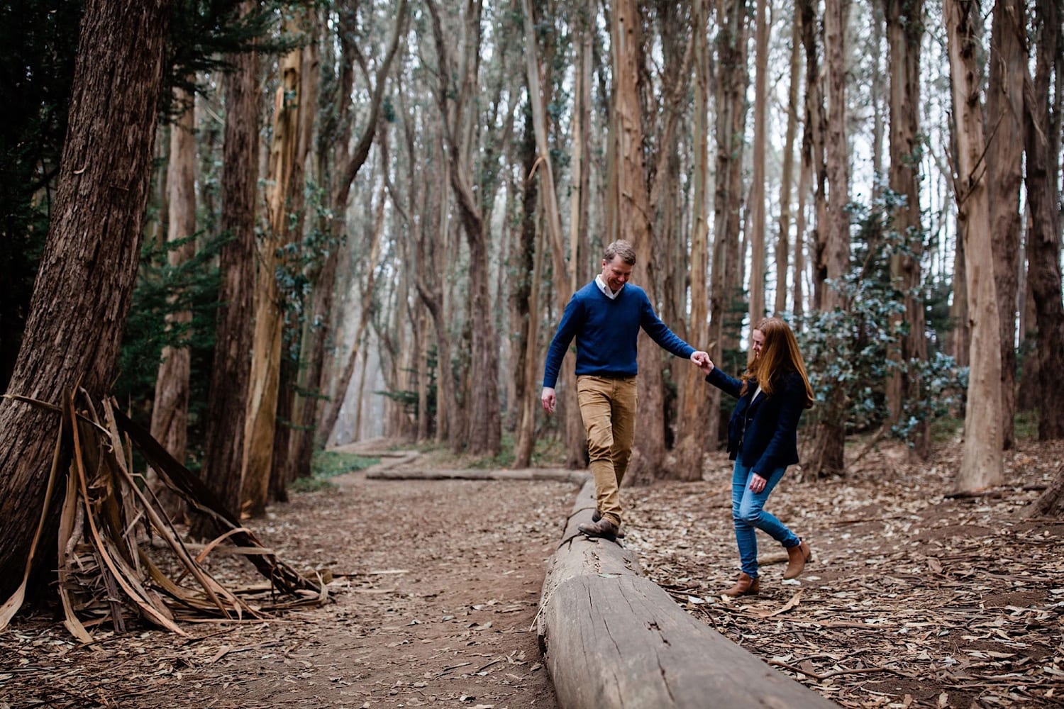 Dad balances on the wood line log holding mom's hand