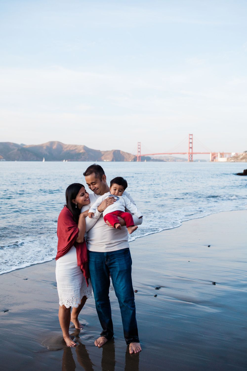Family with toddler at China Beach San Francisco with Golden Gate Bridge in background, lifestyle family photography