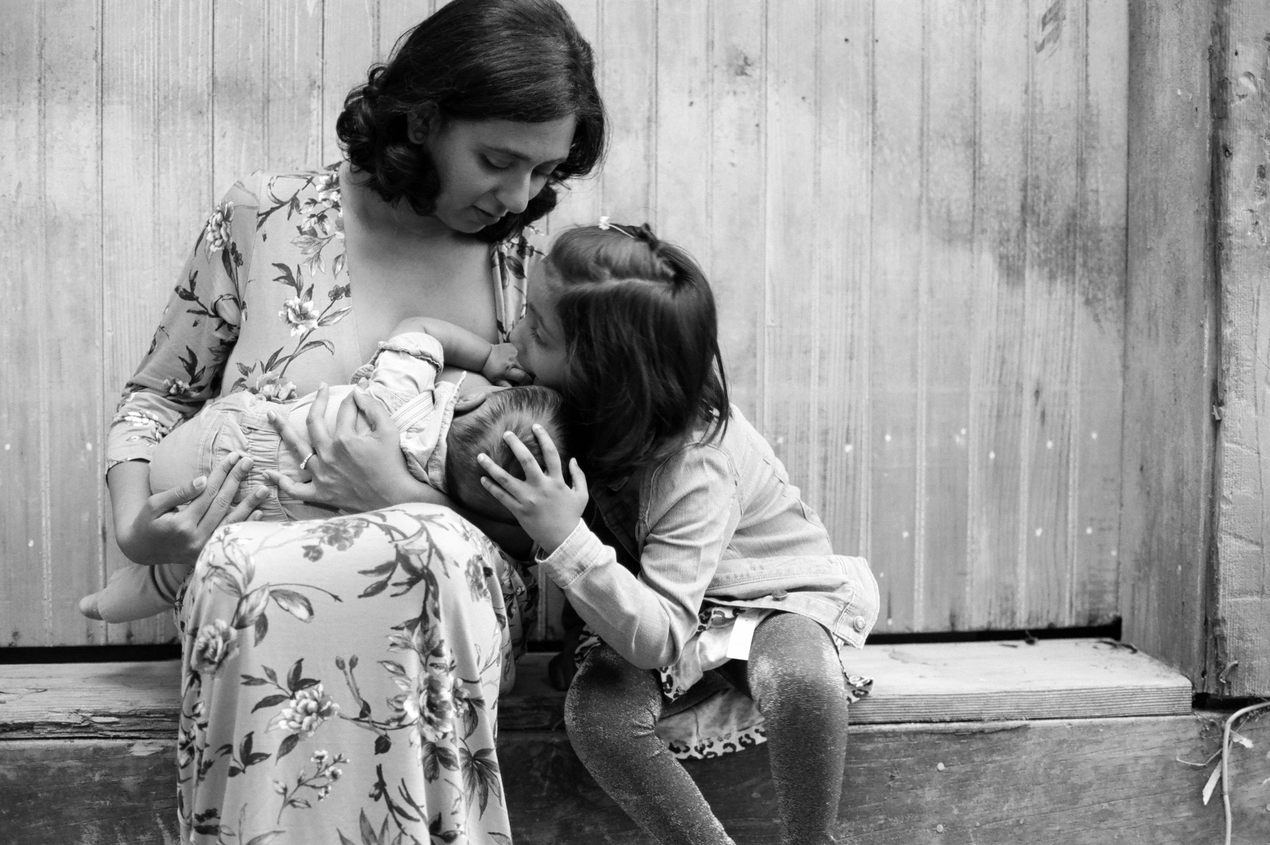 Black and white portrait of a mother with her children against a wooden fence