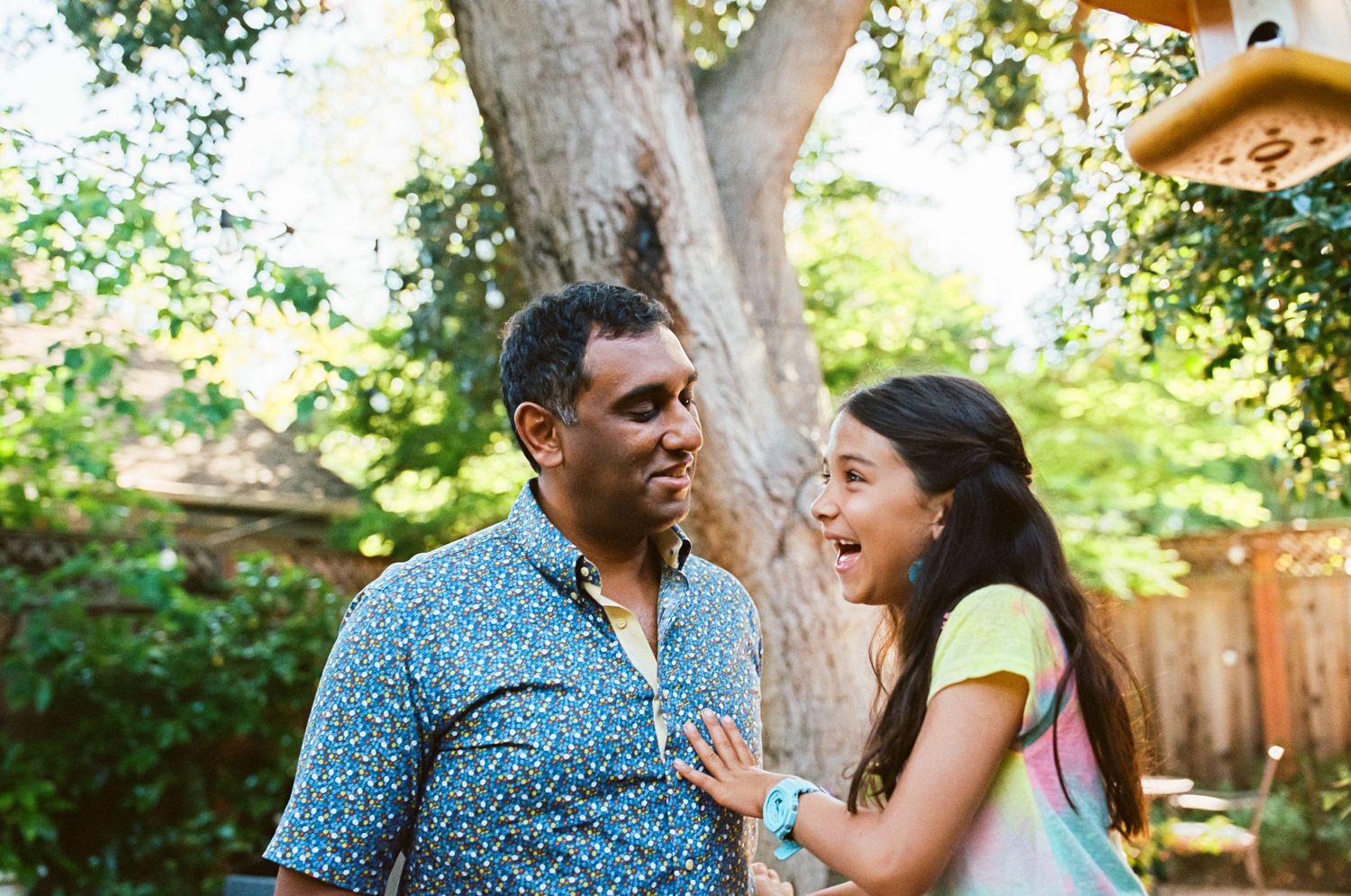 Couple sharing joyful moments together in a sunny backyard — in-home family session