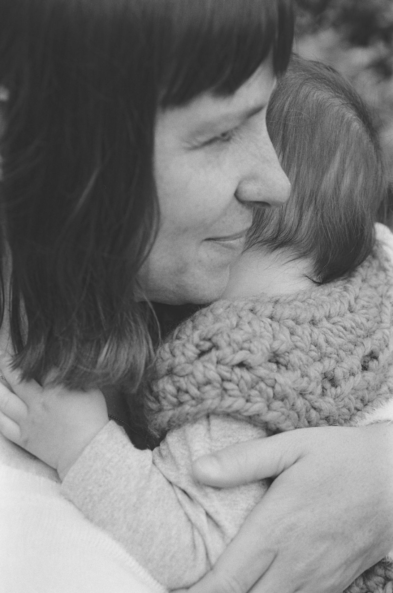 Woman in profile with eyes closed, wearing a textured knit cowl neck sweater, showing tender contemplation