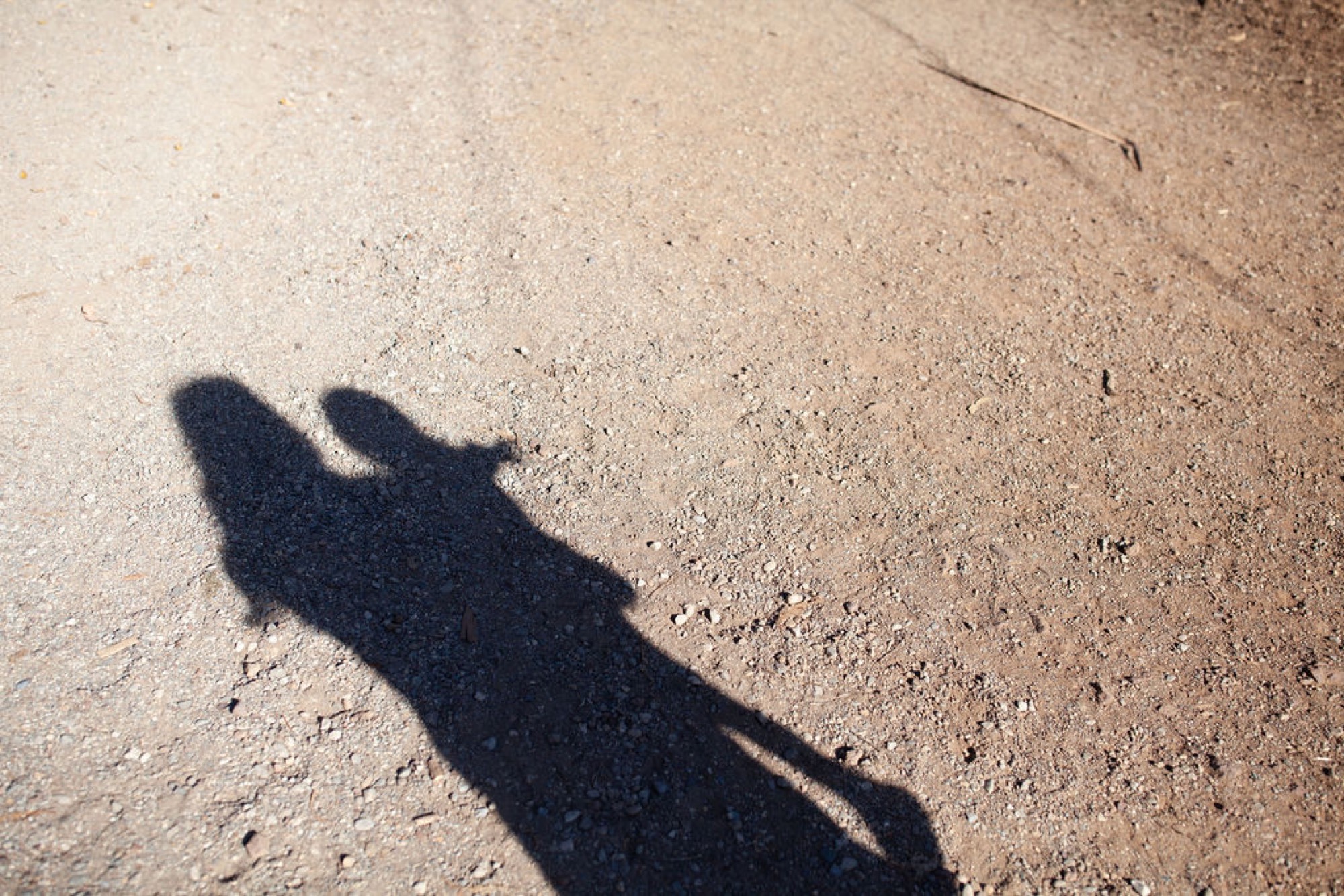 A lone figure's shadow stretches across dusty ground, arms outstretched in a moment of carefree movement