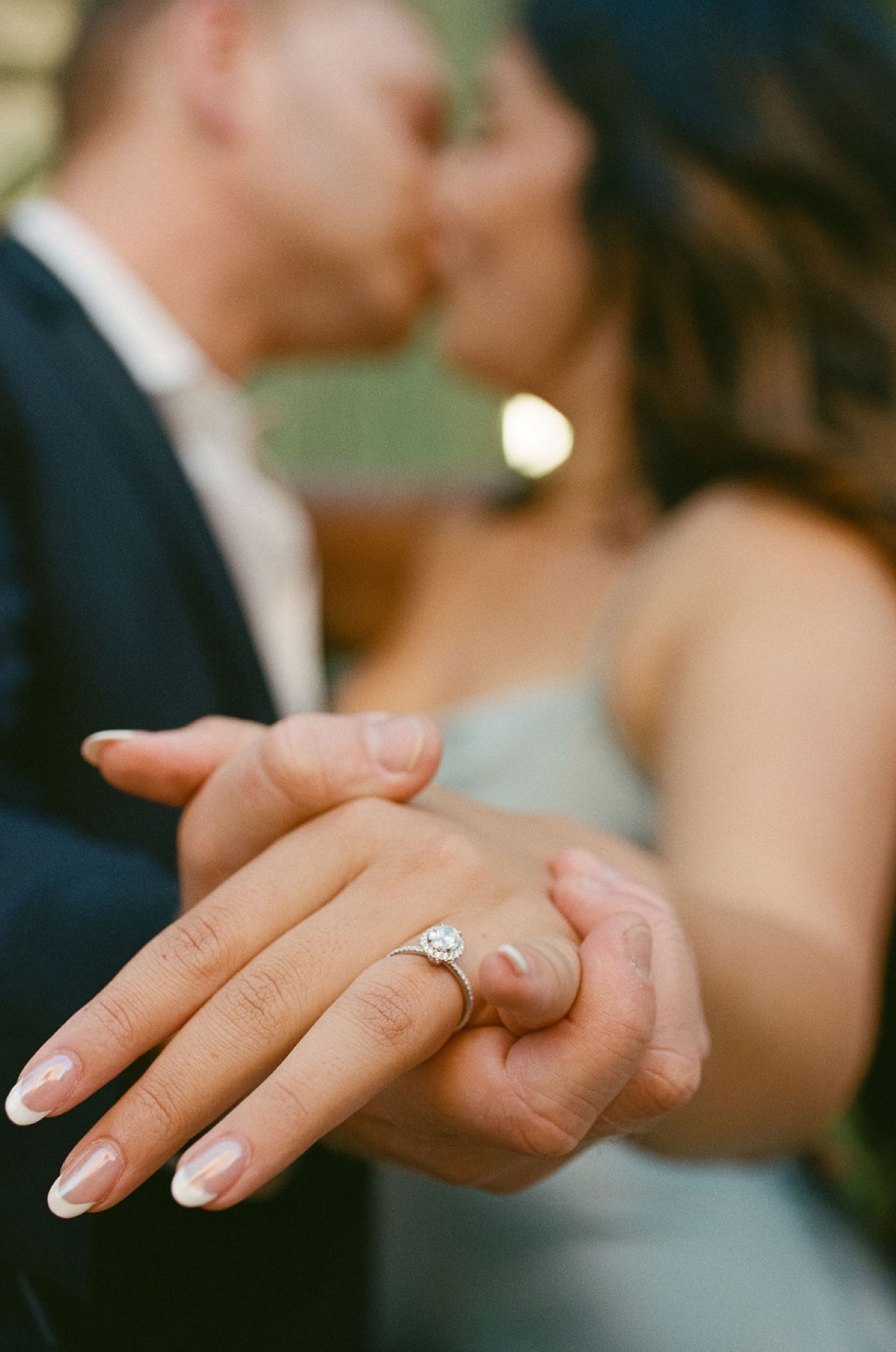 Newlyweds display their wedding rings with hands clasped together, soft natural light illuminating the diamond band and gold settings