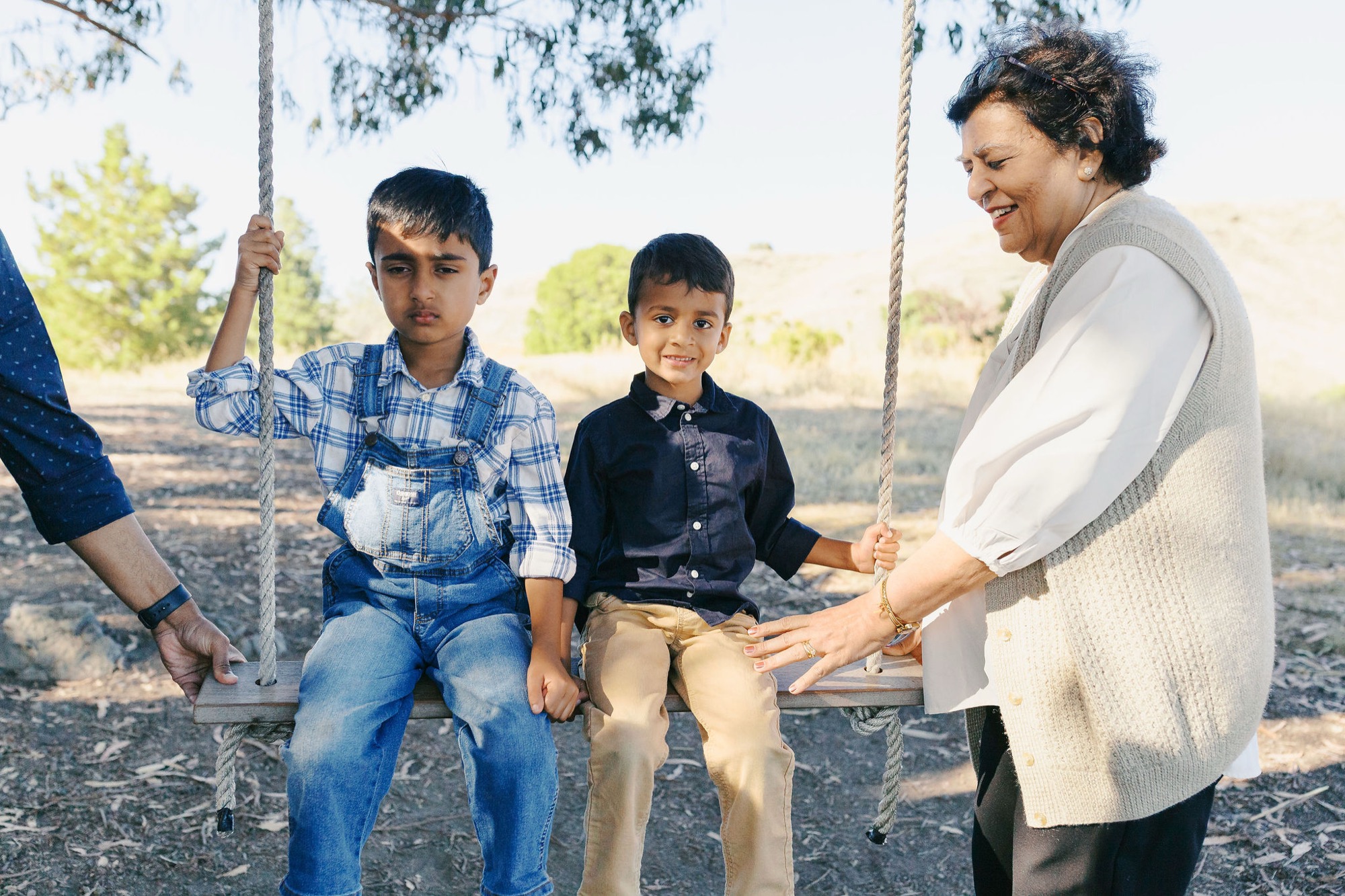 Marin family photographer captures a sweet moment between a grandmother and her two grandsons sharing a rope swing outdoors, the warmth and love between three generations glowing in soft natural light. A beautiful candid from this extended family session in Marin County.