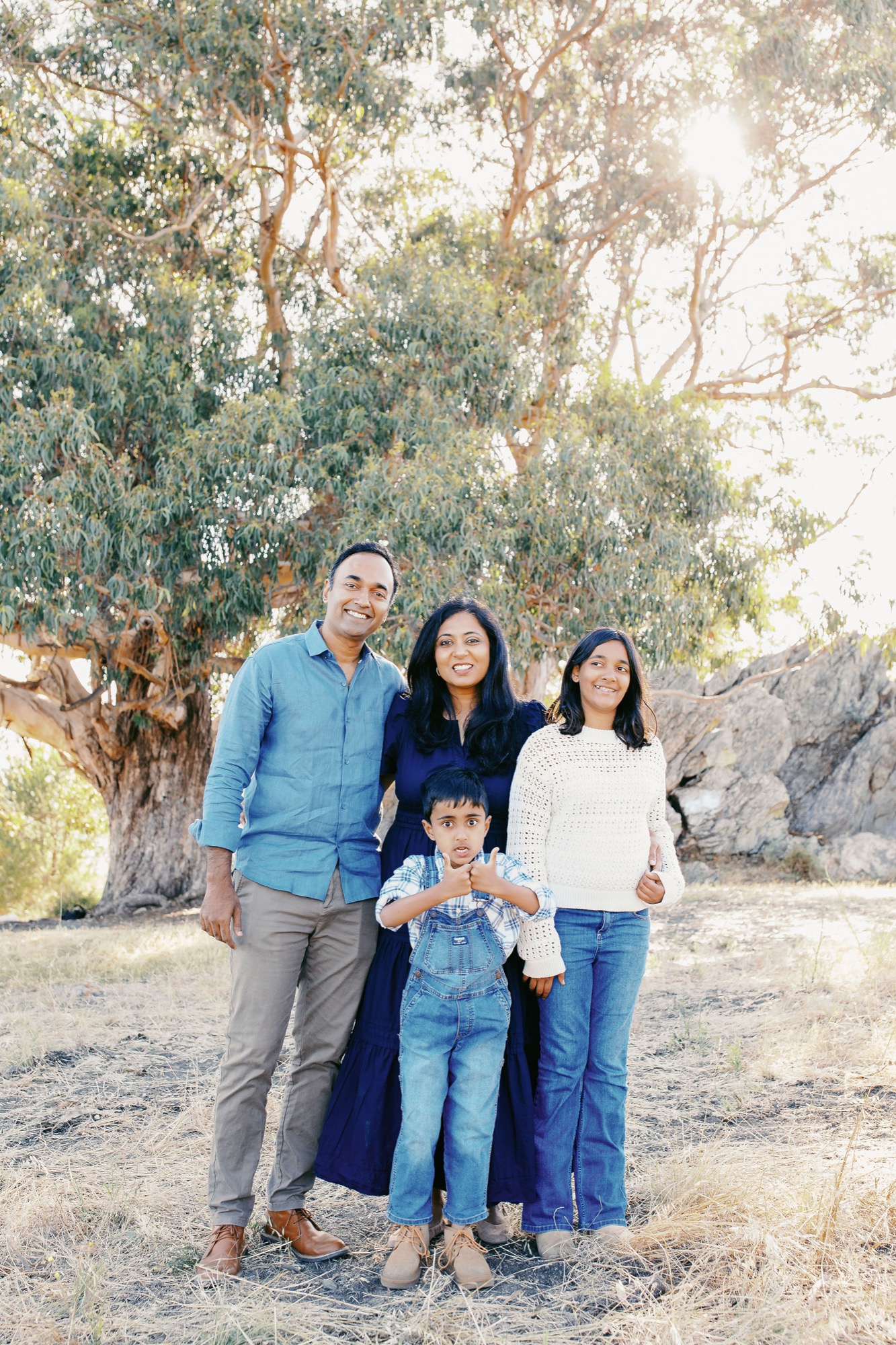 Marin family photographer captures a warm and sun-drenched family portrait beneath a sweeping eucalyptus tree — genuine smiles and natural connection radiating in the soft golden backlight of a Marin County outdoor mini session.