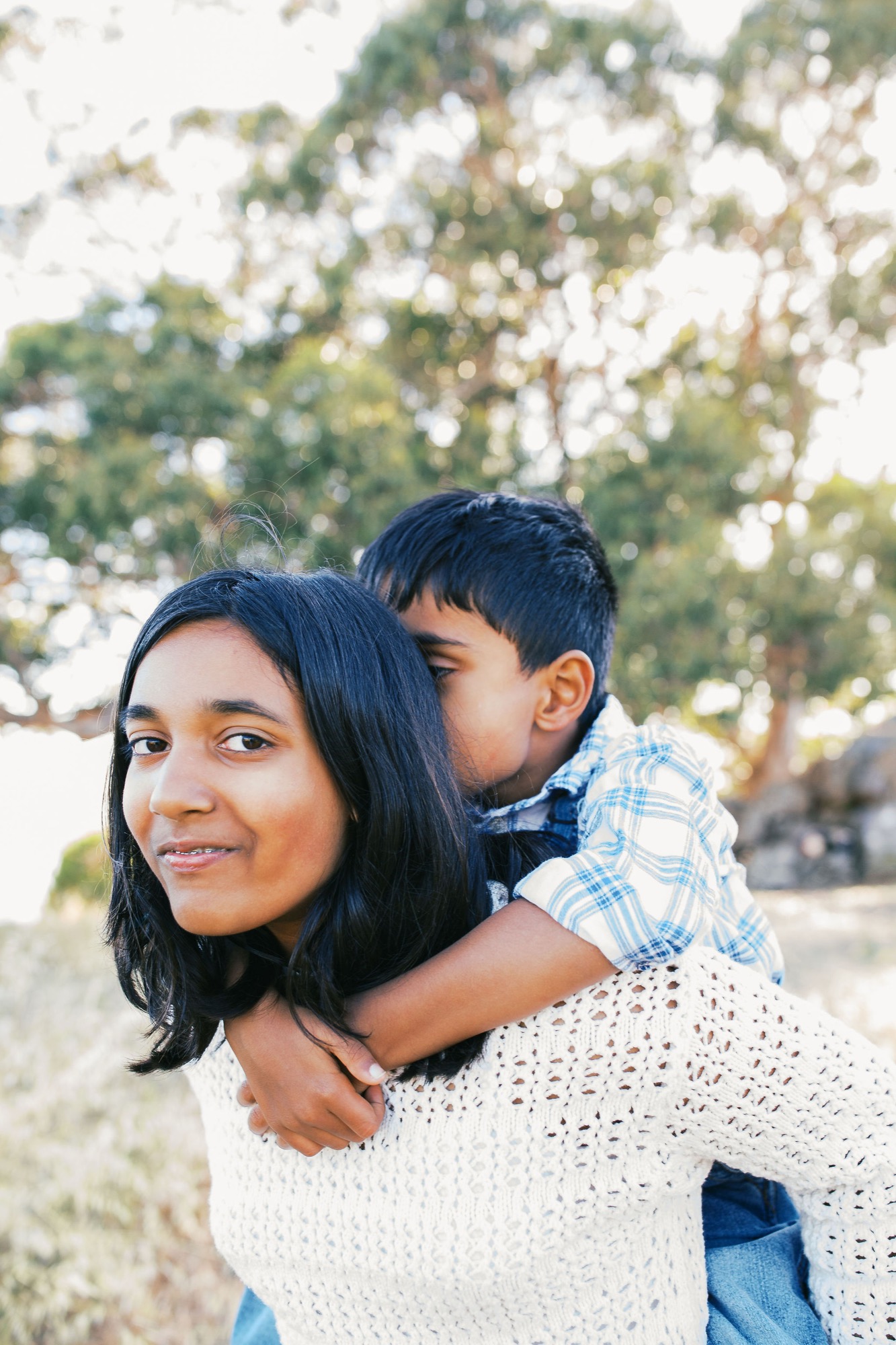 Marin family photographer captures a tender moment as a young boy wraps his arms around his mom and steals a kiss during an outdoor family session in Marin County — soft natural light and genuine connection at the heart of this Bay Area lifestyle family portrait.