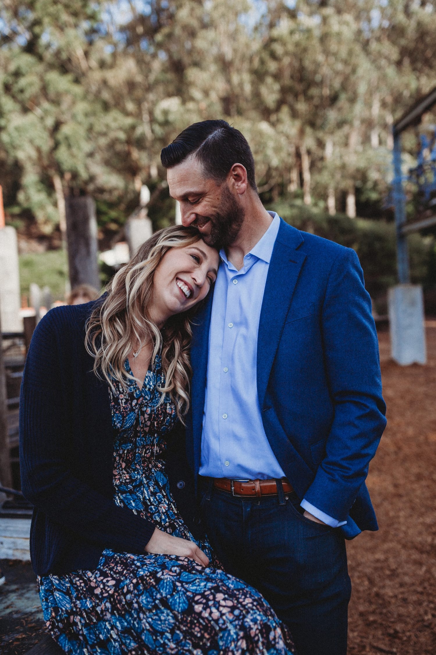 Mom rests her head on dad's shoulder as they laugh together outdoors