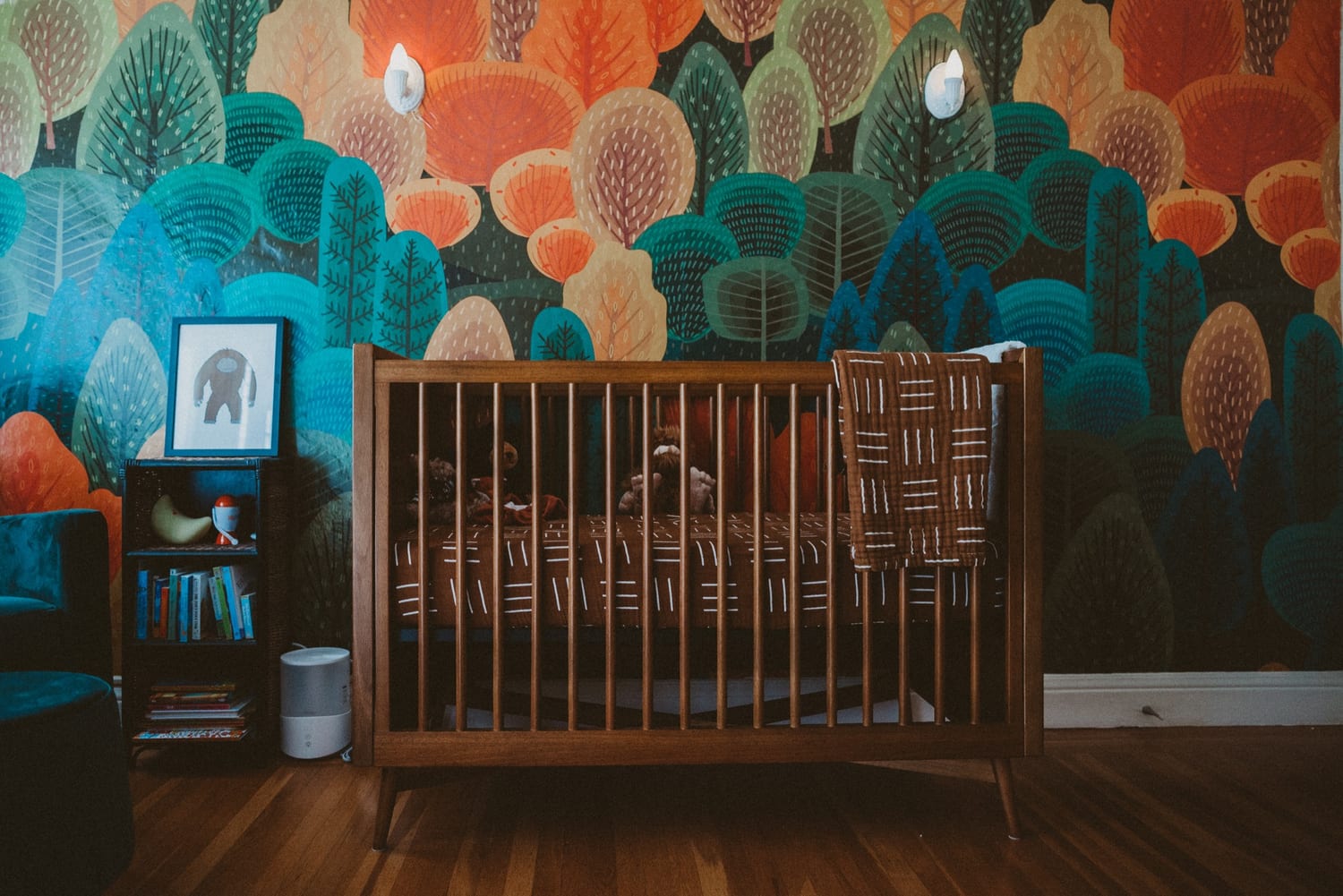 Wooden crib against a vibrant forest mural wall in the San Francisco nursery