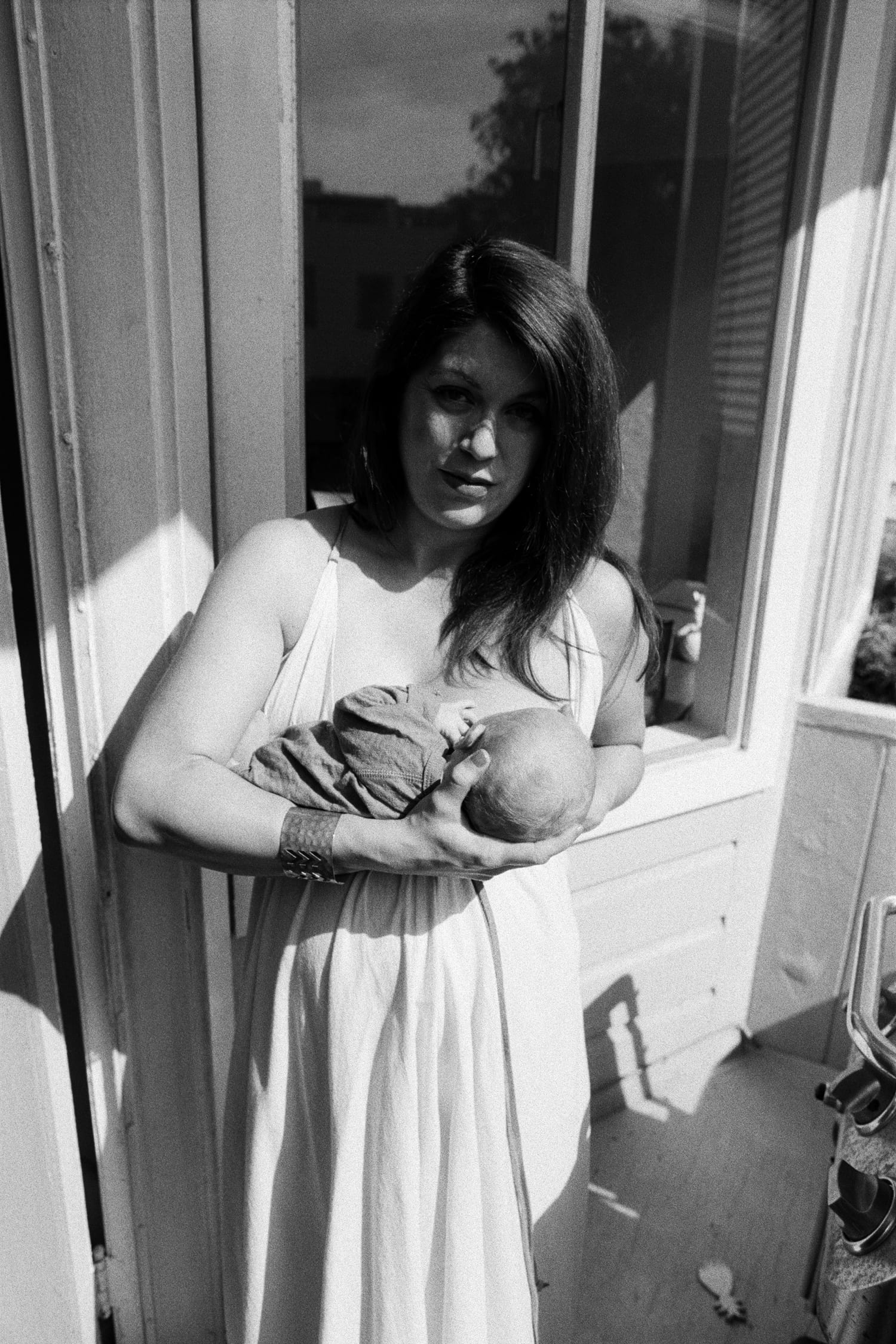 Black and white portrait of mom in a white dress cradling her newborn