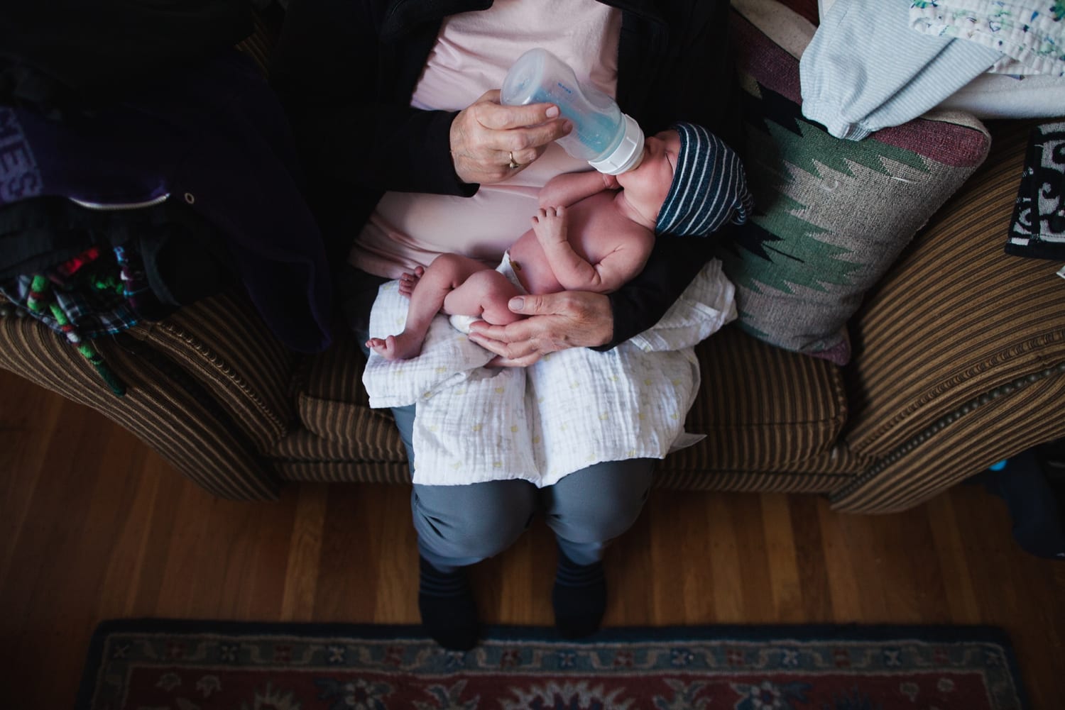 Overhead view of the newborn taking a bottle in a family member's lap