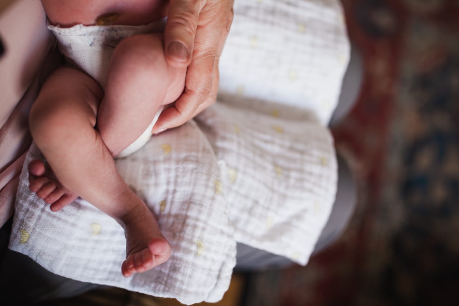 Close-up of newborn legs and feet crossed on a muslin swaddle blanket