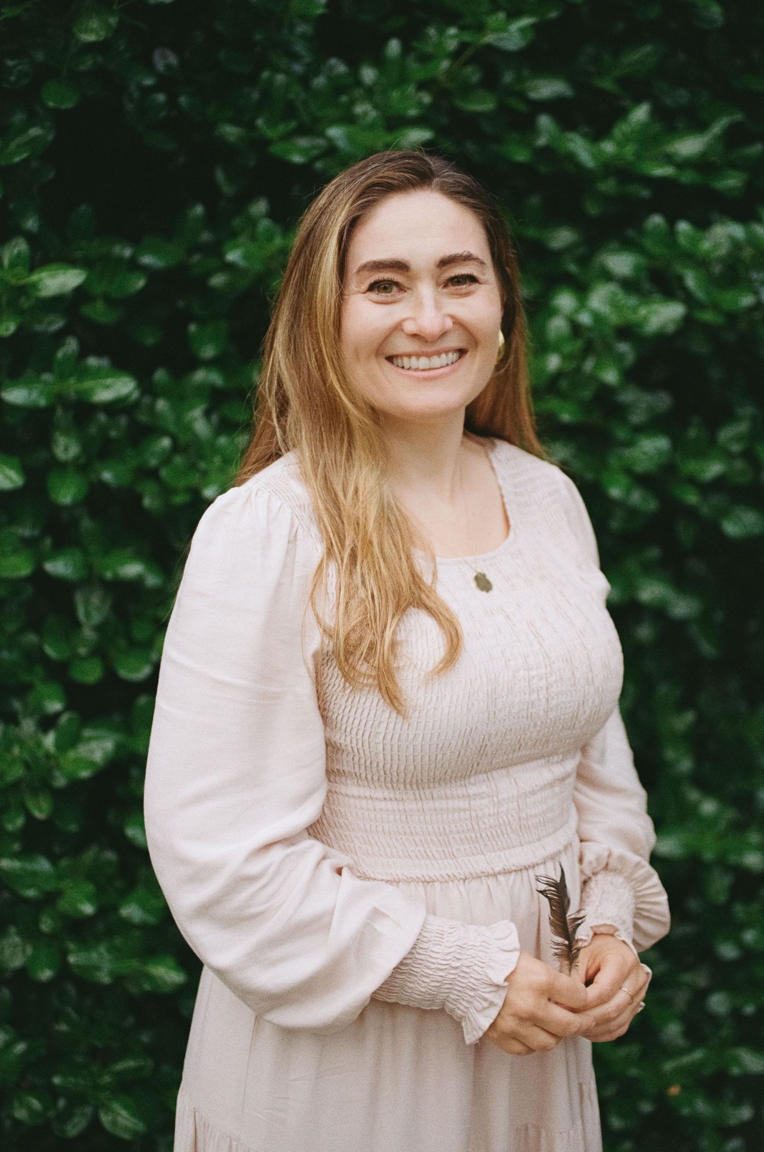 Warm outdoor headshot portrait against a dark green hedge backdrop — San Francisco