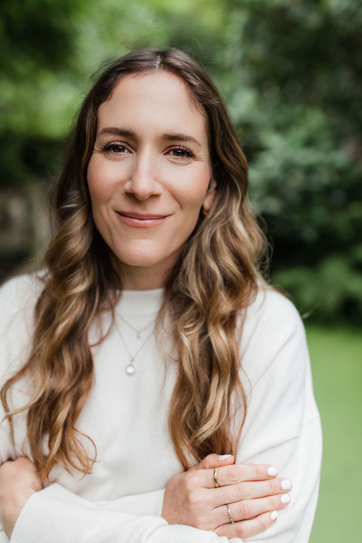 Close headshot portrait with soft green foliage background — natural light photography in Marin County