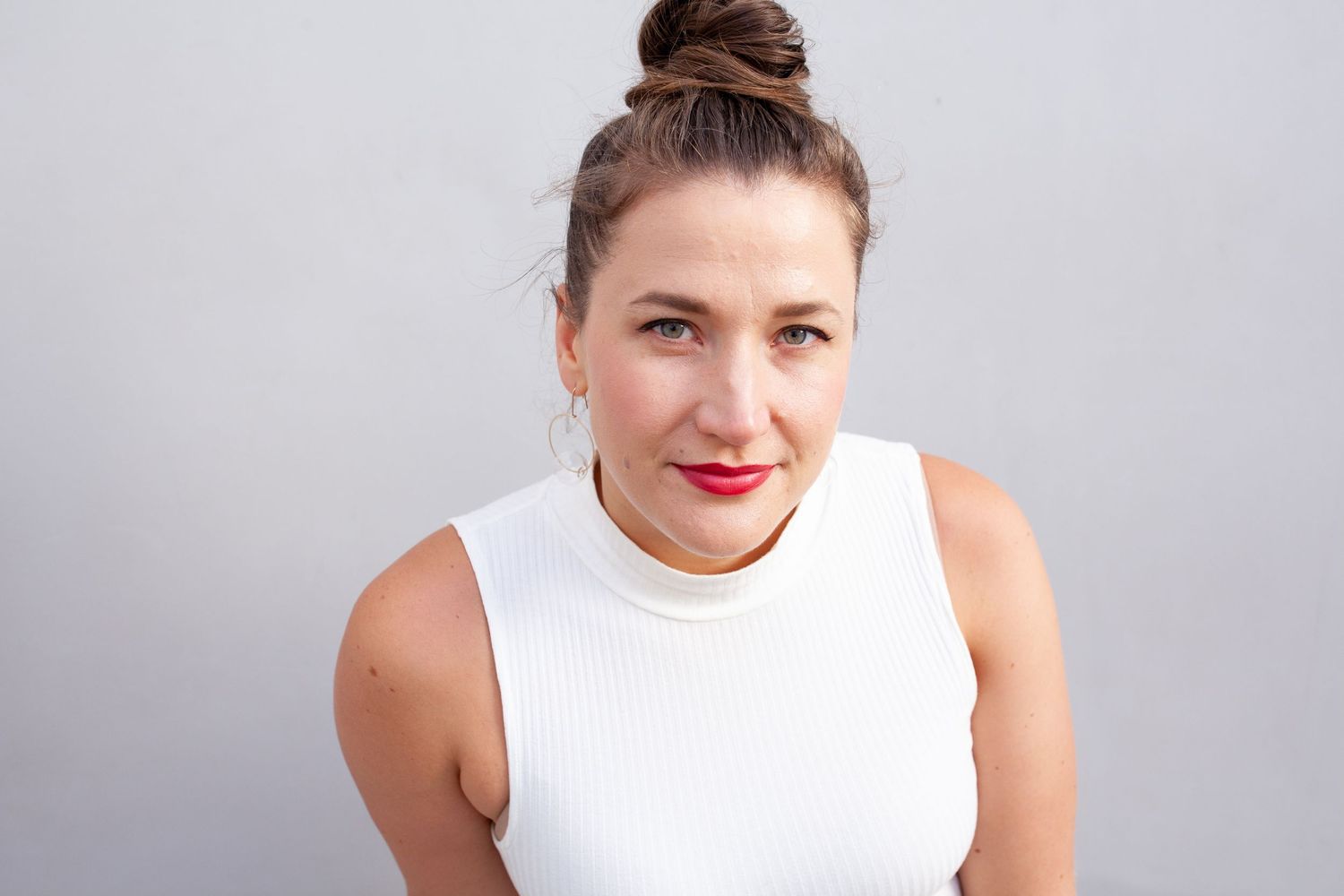 Minimalist studio headshot in a white sleeveless top — clean professional portrait