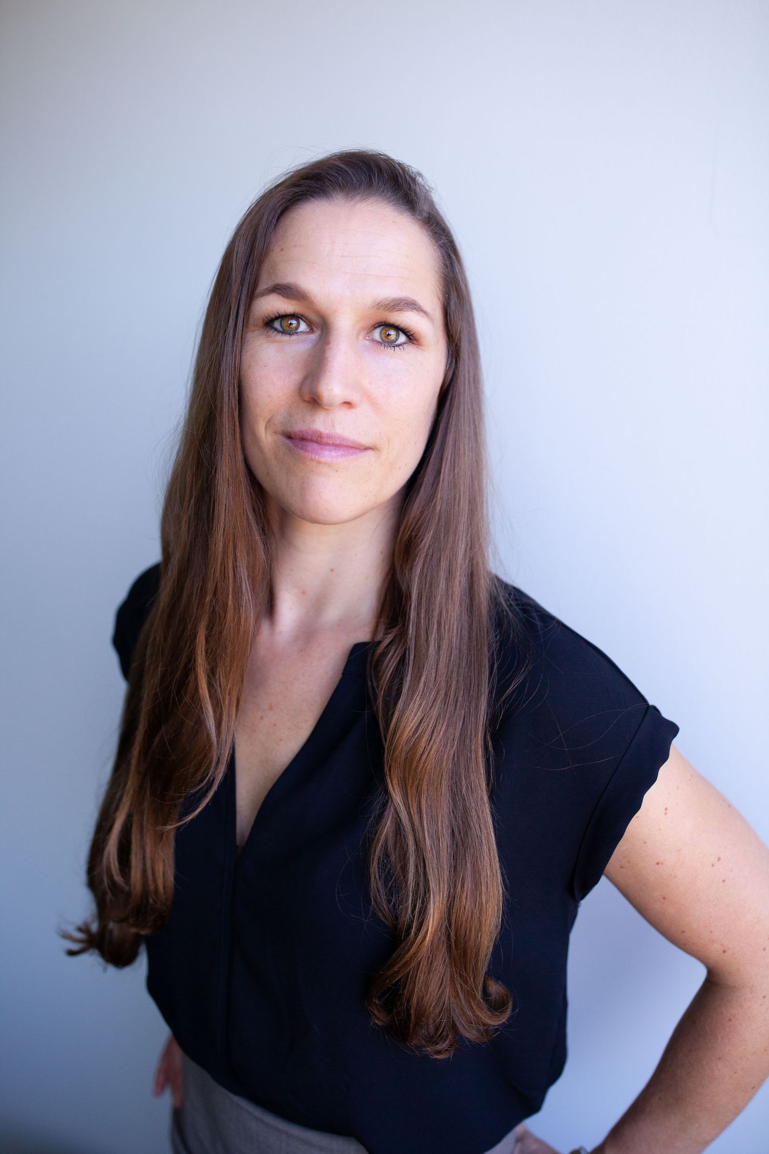 Clean professional headshot in a black top against a light gray background