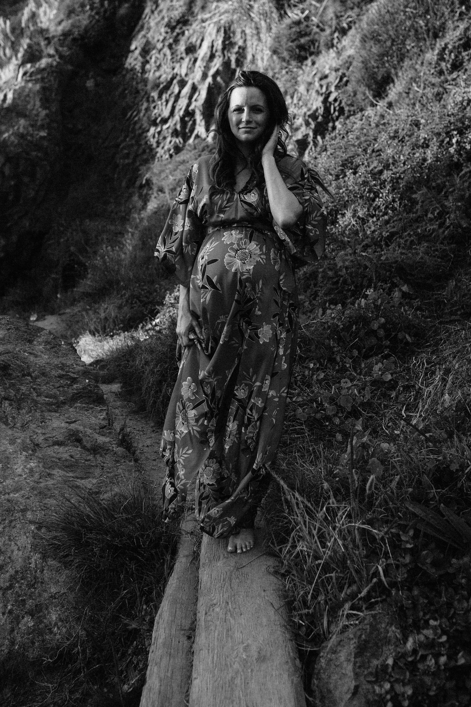 Black and white maternity portrait on a wooden log in nature