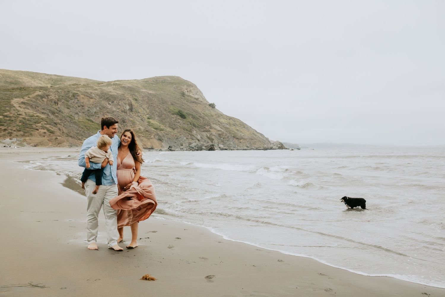 Family laughing on a misty Bay Area beach with their dog — maternity session