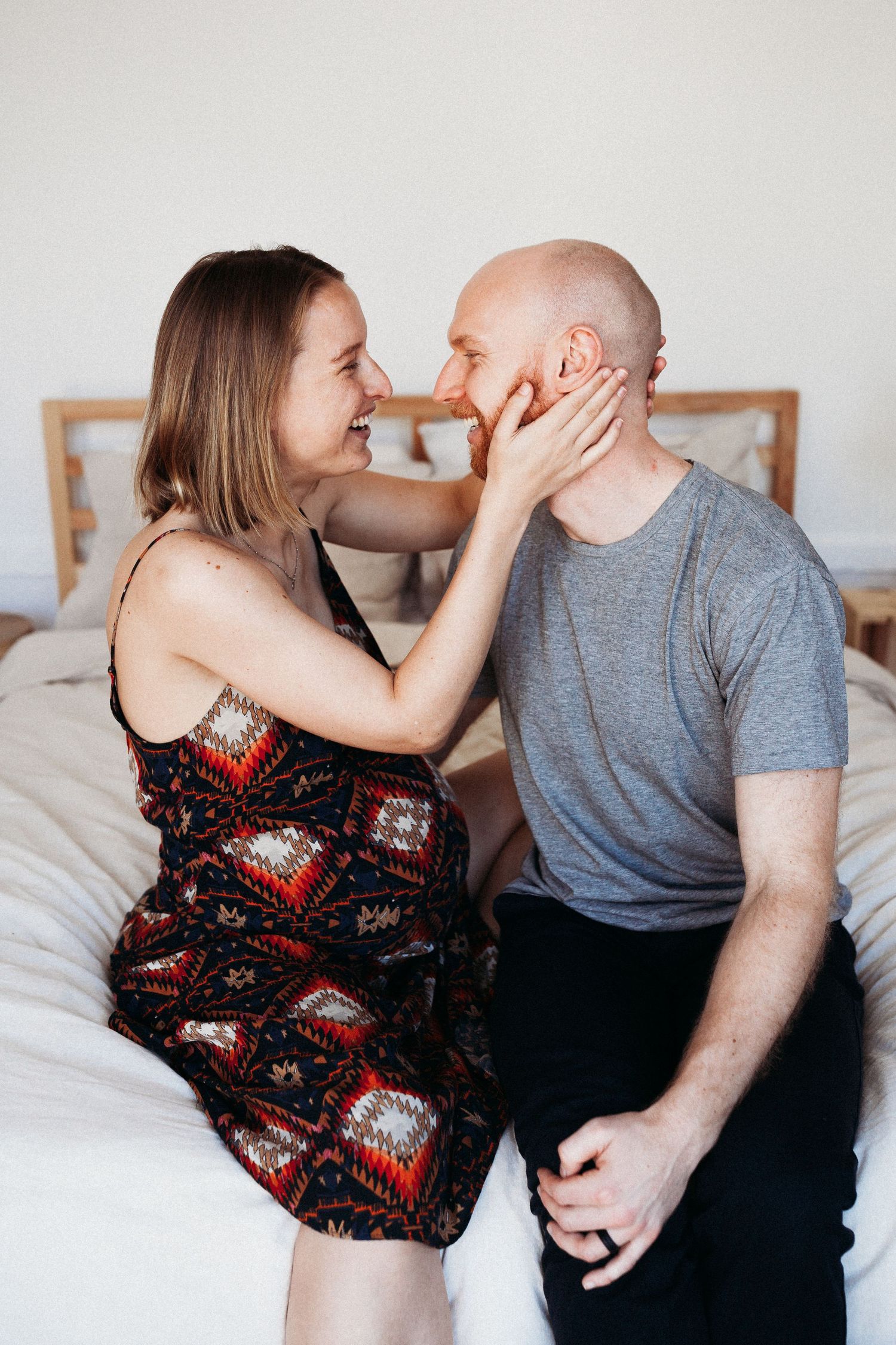 Intimate moment between an expectant couple on a bed — in-home maternity session in Marin County