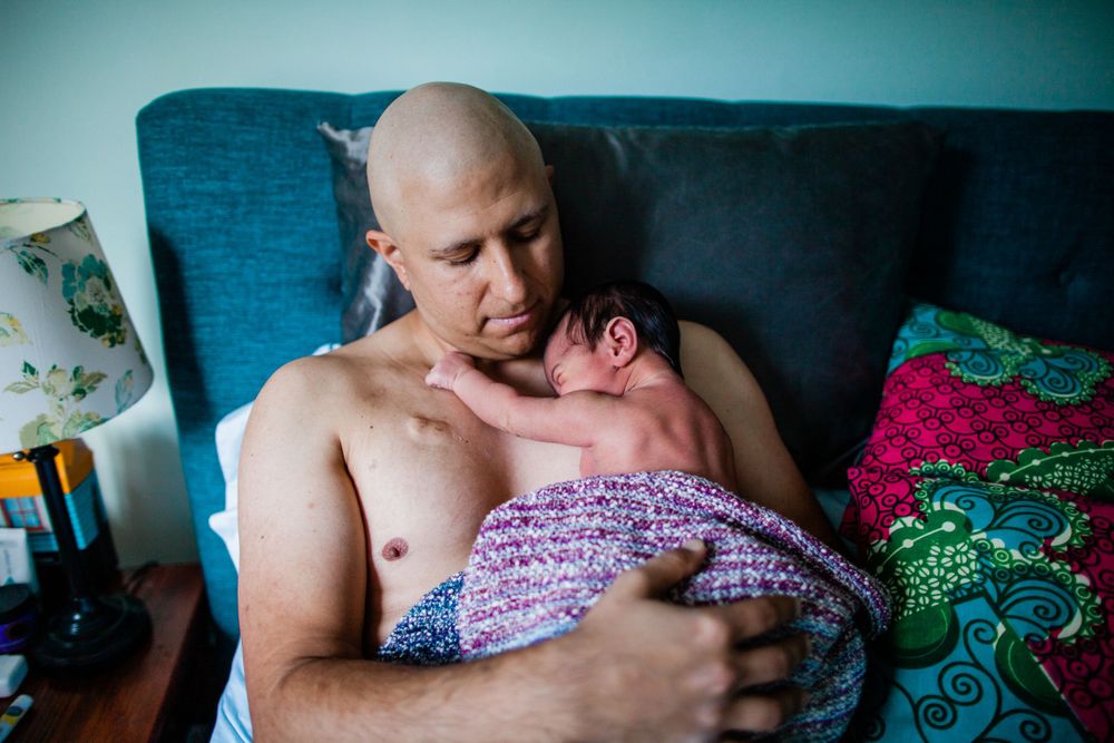 Father holding newborn skin-to-skin on a sofa at home — San Anselmo Newborn Photographer
