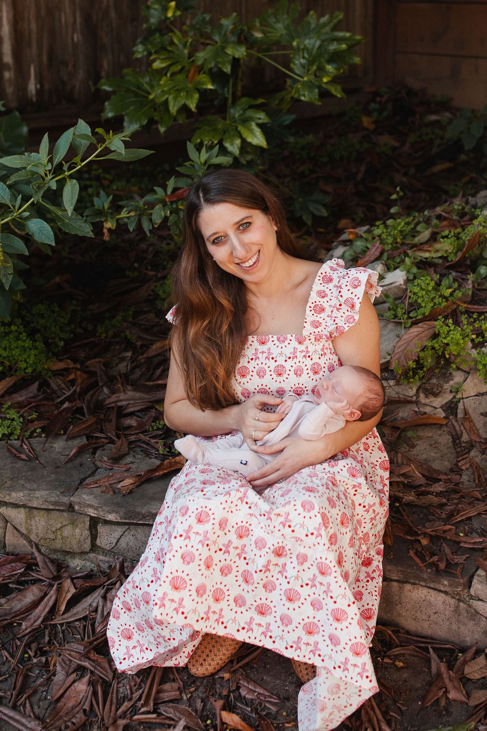 Mother smiling in a garden holding her sleeping newborn — San Anselmo Newborn Photographer