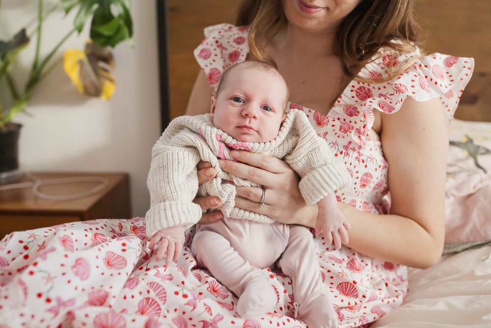 Mother in floral dress holds newborn in knit sweater — San Anselmo Newborn Photographer
