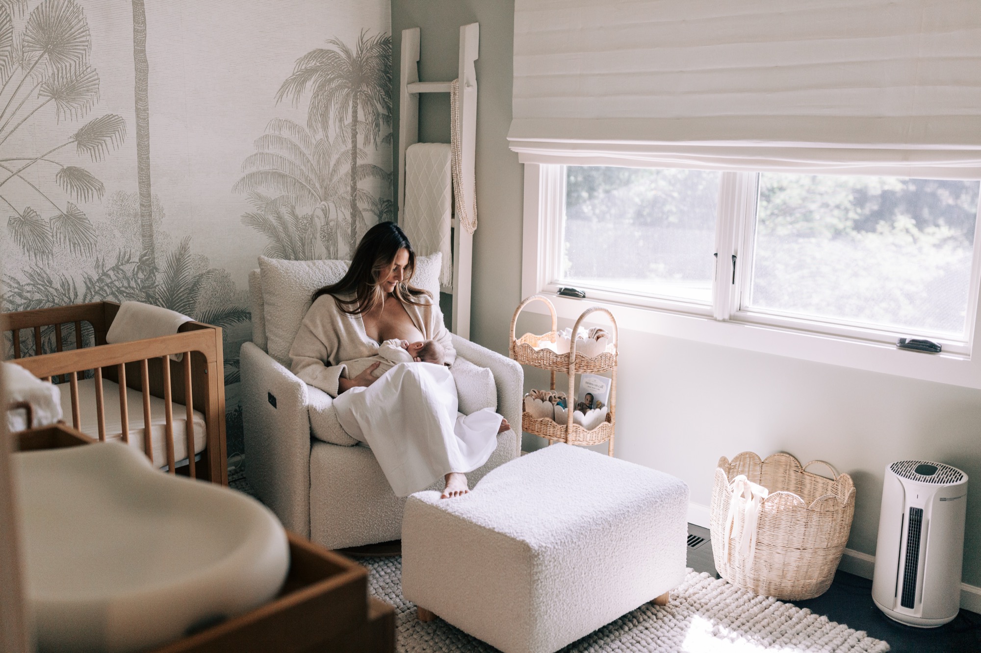 A new Marin County mama nurses her newborn in the soft morning light of their carefully crafted nursery, palm mural wallpaper and a cozy boucle glider framing a moment of pure, quiet devotion. This is the kind of image that captures not just a baby, but the whole world a family built for them.