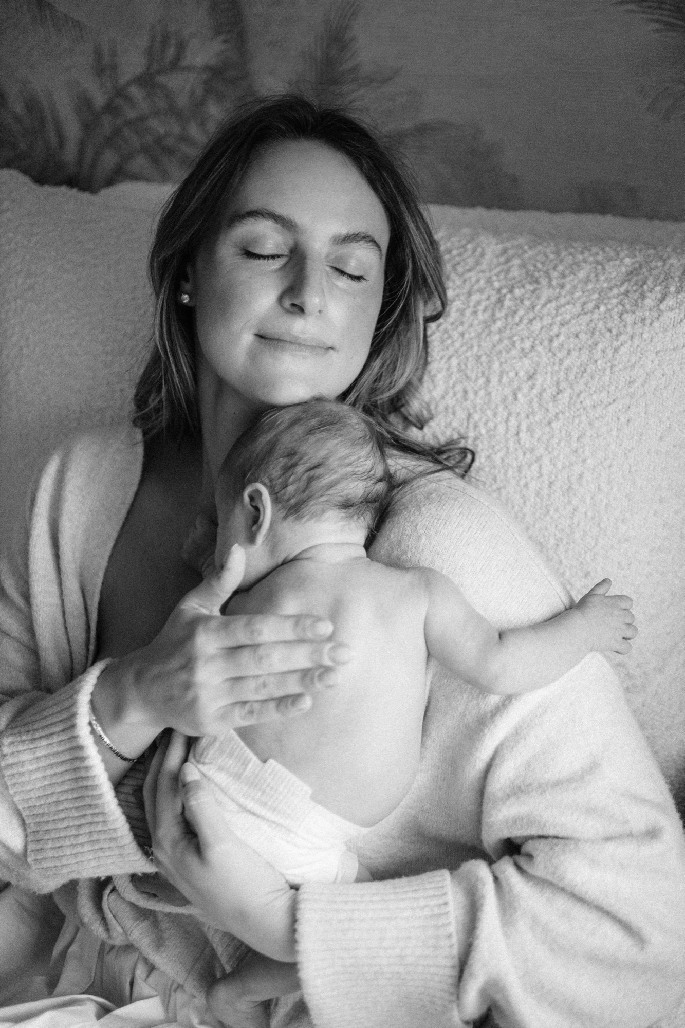 Mother with eyes closed holding her newborn skin-to-skin — in-home lifestyle session in Marin County