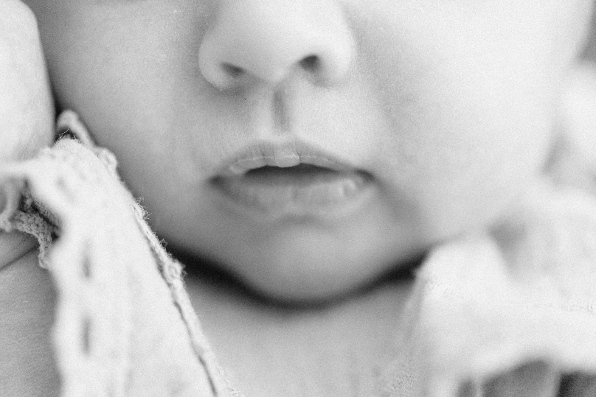 Close-up of a newborn's bow-shaped lips and cheeks in a knit wrap