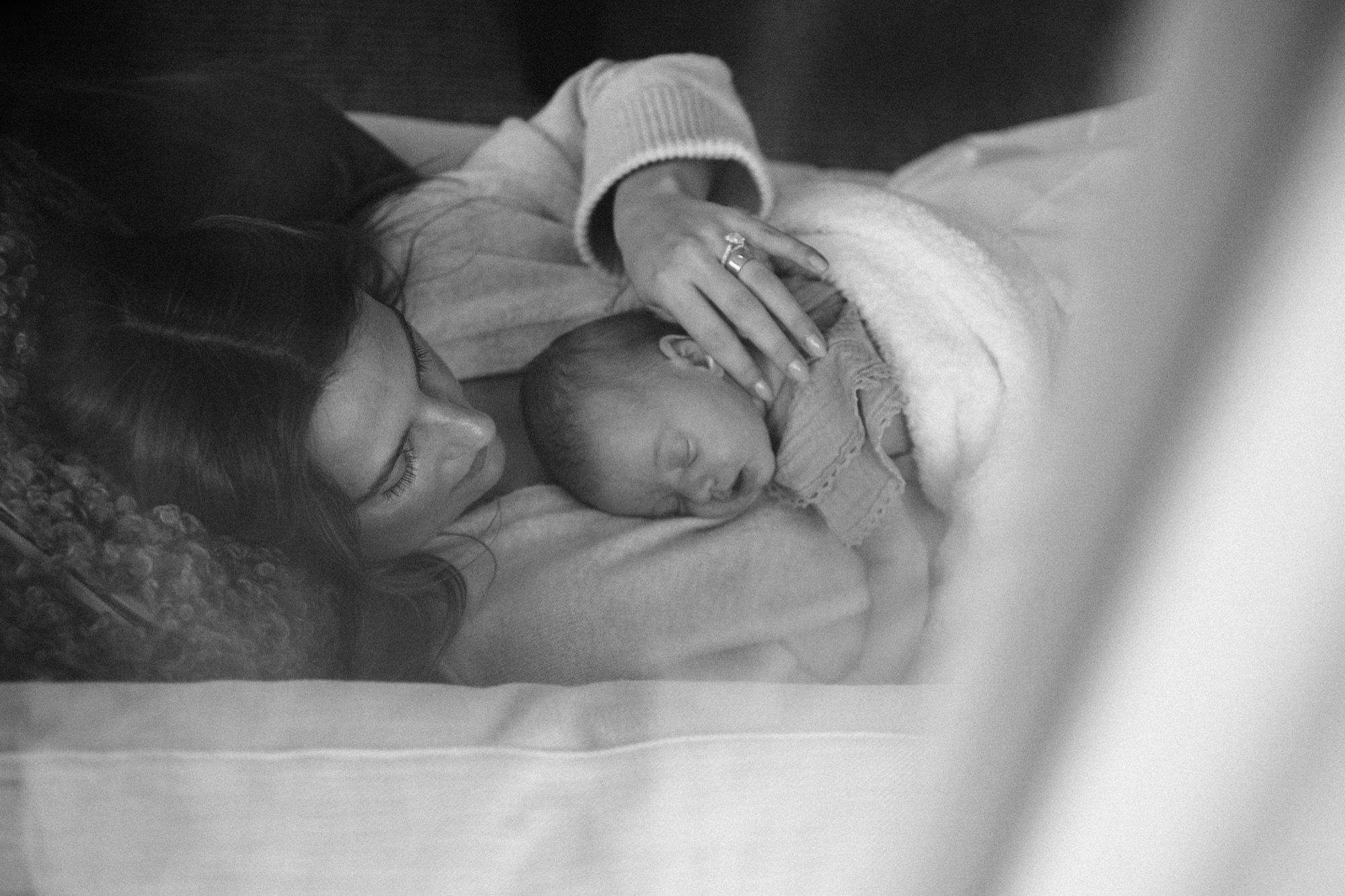 Victoria lies face-to-face with sleeping baby Gwen, cradling her head
