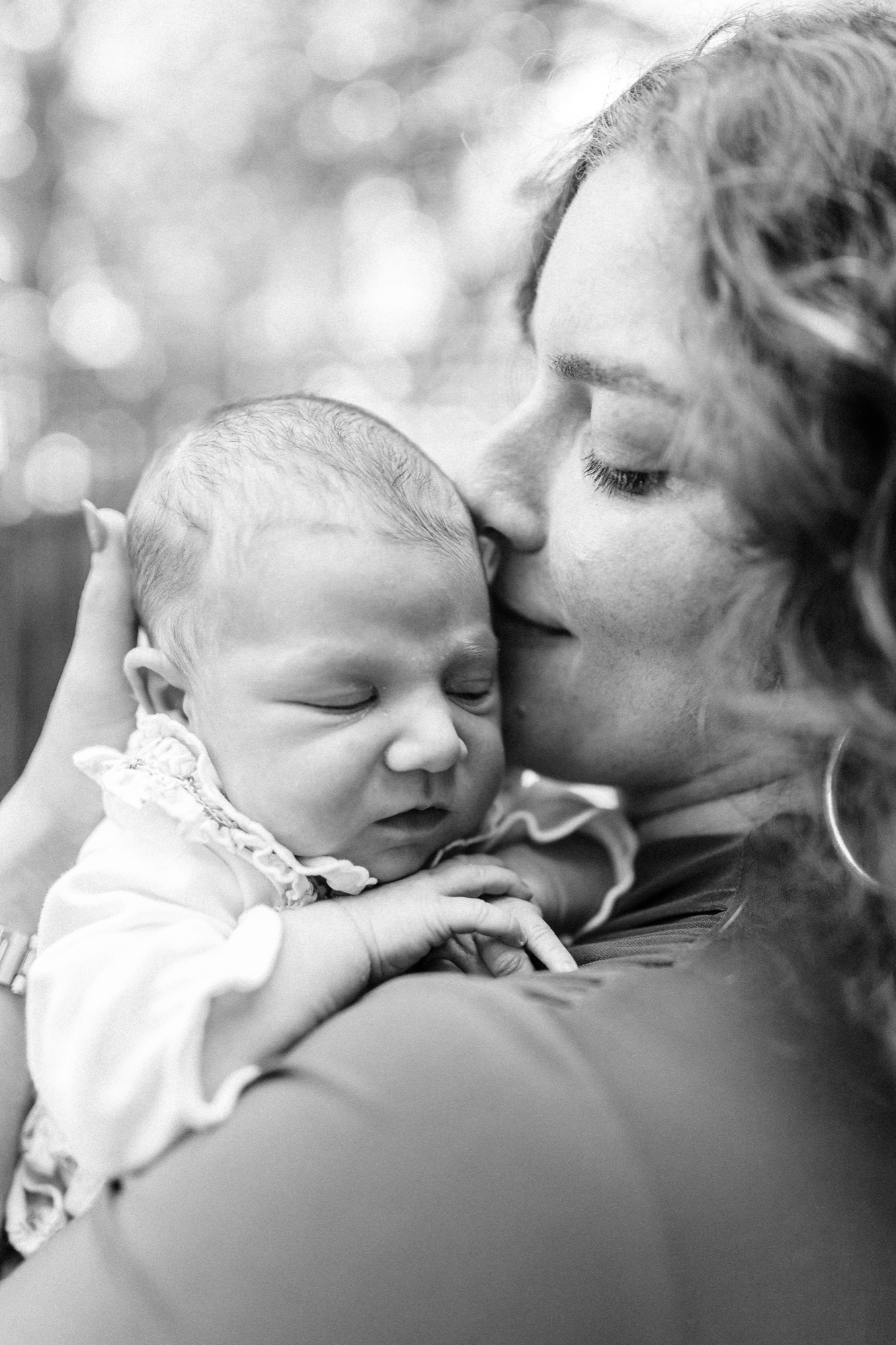 Marin newborn photographer captures a mother tenderly nuzzling her two-week-old daughter in soft dappled light at their Palo Alto home — an intimate lifestyle newborn portrait full of quiet, unguarded love.