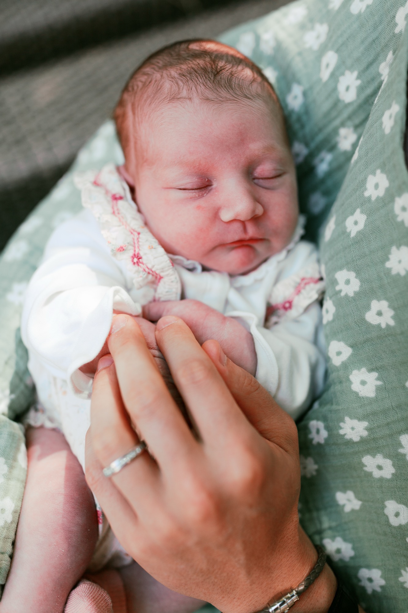 Marin newborn photographer captures a tender moment as a parent's ringed hand gently cradles the tiny hands of two-week-old Dalia during a lifestyle newborn session at their Palo Alto home — intimate Bay Area newborn photography.