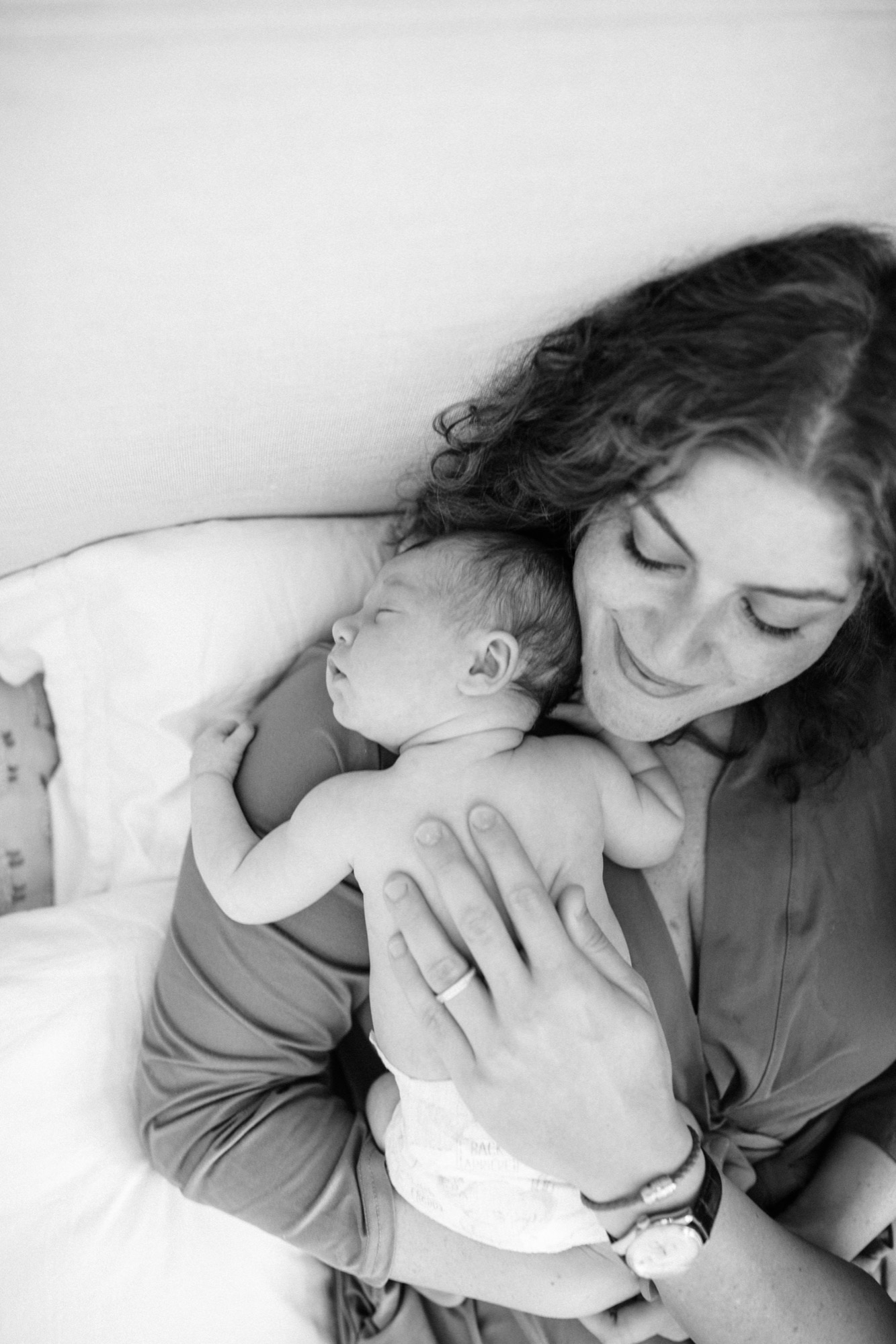 Marin newborn photographer captures a mother gazing down at her sleeping two-week-old in soft, luminous light at their Palo Alto home — a tender moment of early motherhood preserved through lifestyle newborn photography in the Bay Area.