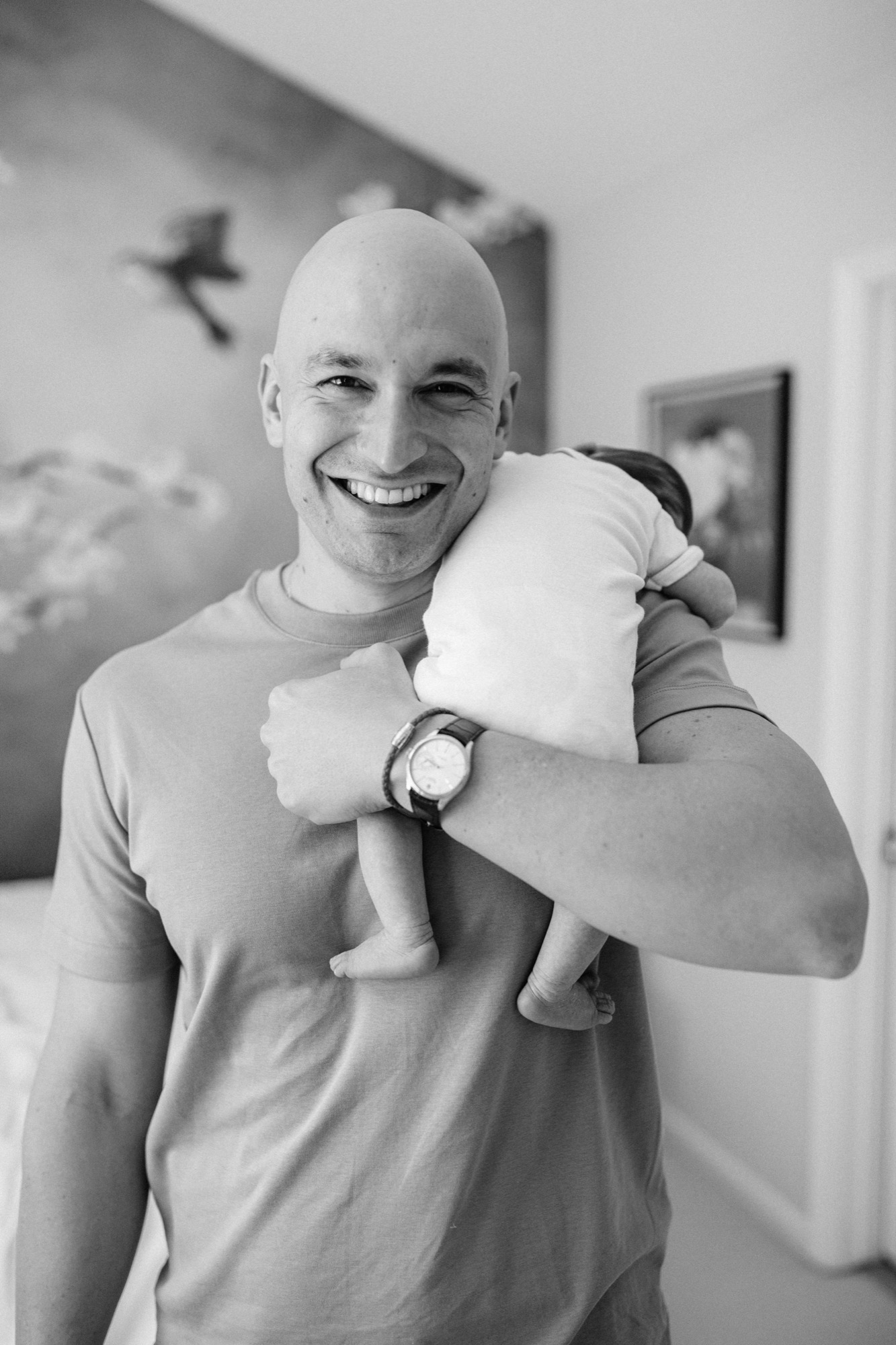 A father cradles his newborn over his shoulder in soft natural light (Bay Area lifestyle newborn photography)