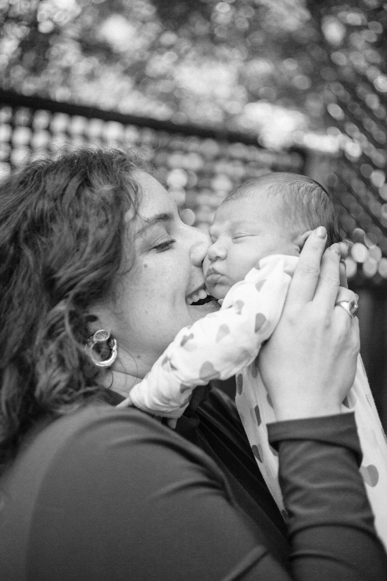 A parent gazes down at their sleeping newborn with soft afternoon light filtering through the window
