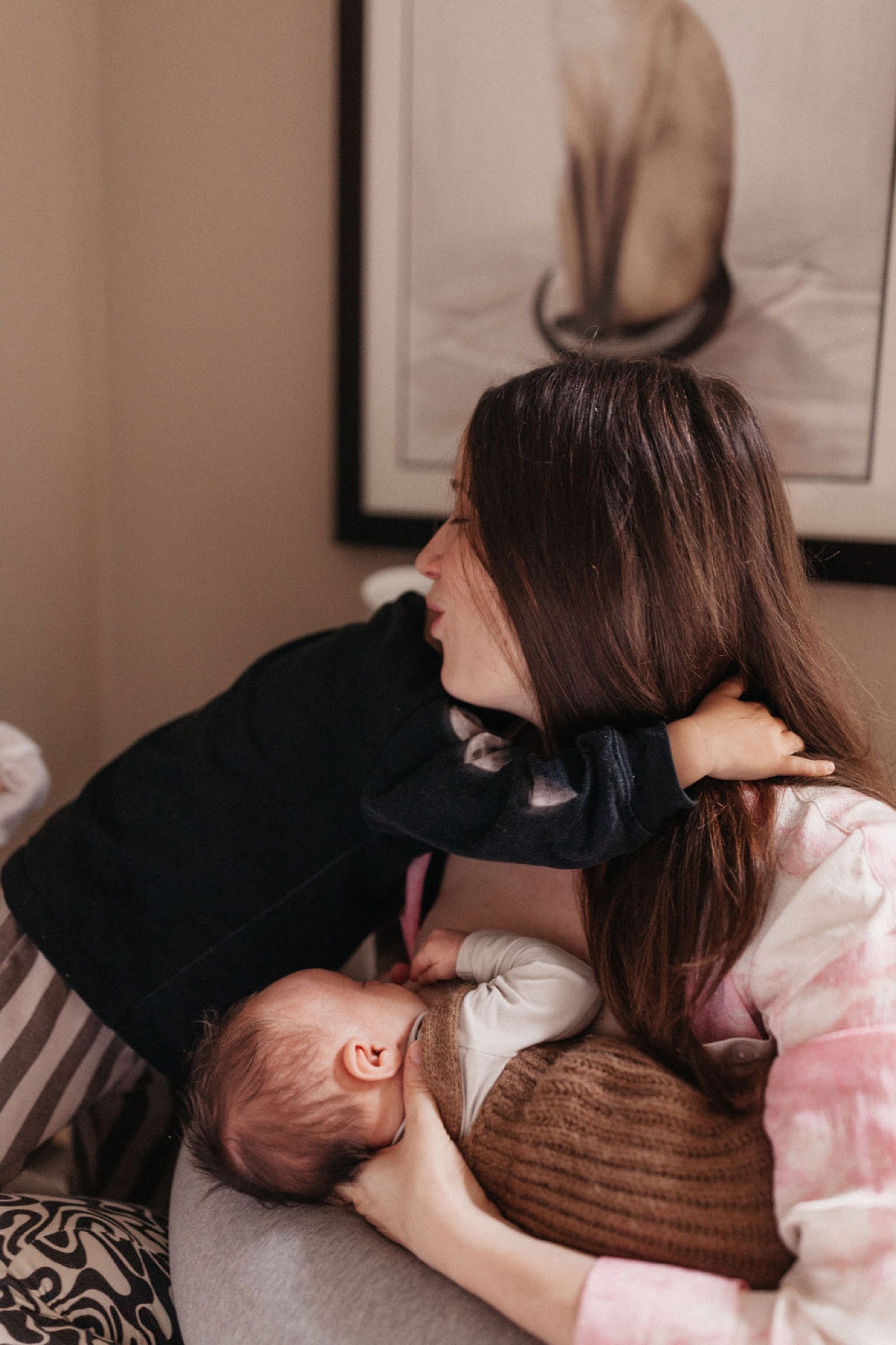 A mother and infant bond on a striped bed, their faces close together in a tender moment of connection and affection