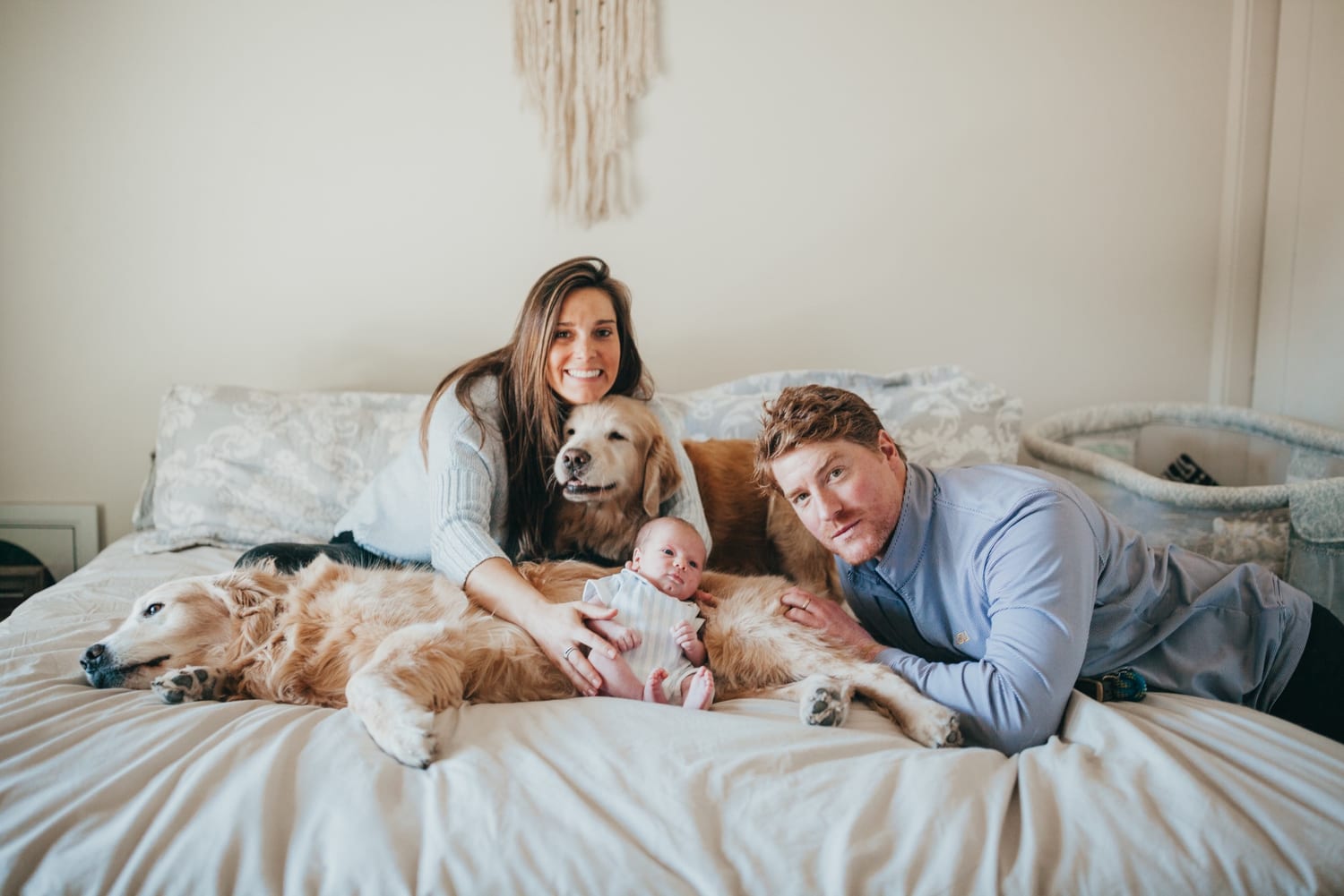 Golden retriever snuggling a newborn on the bed